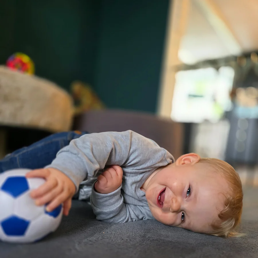 En dreng leger paa babytaeppet med en bold
