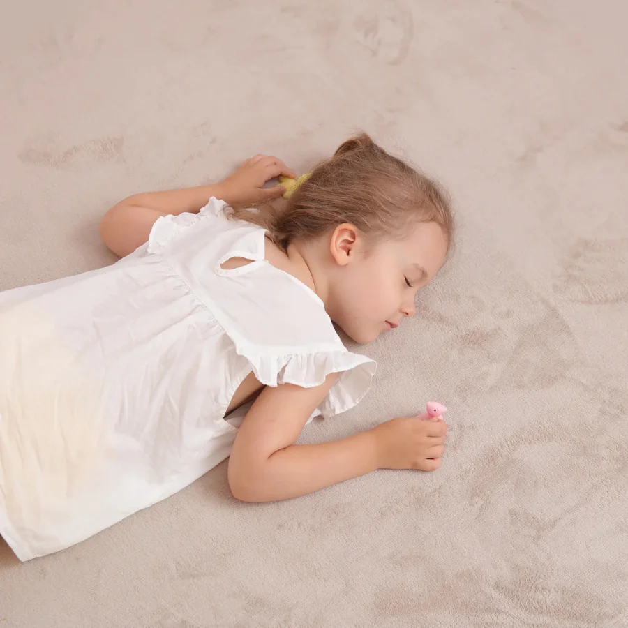 En piger som ligger paa BabyNordic Taeppet