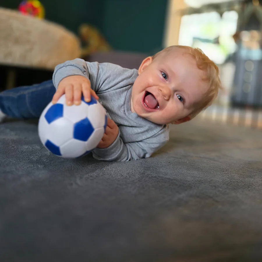 Lille dreng leger med sin fodbold paa Babytaeppet