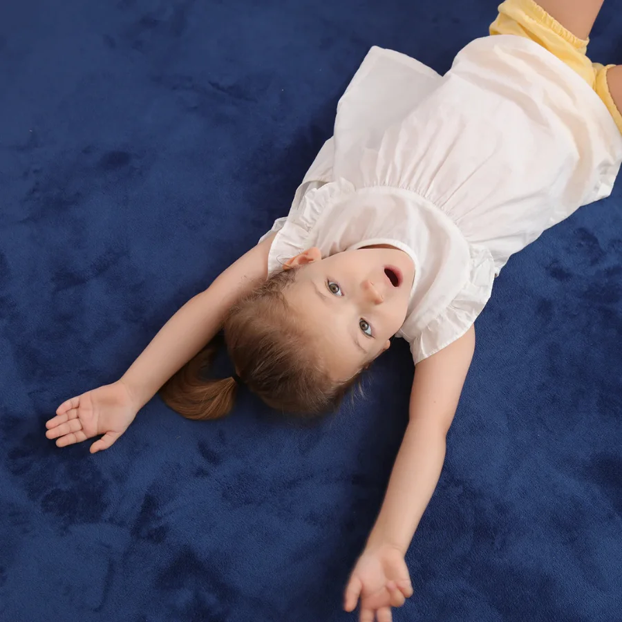 Pige leger paa et moerkeblaat babytaeppe